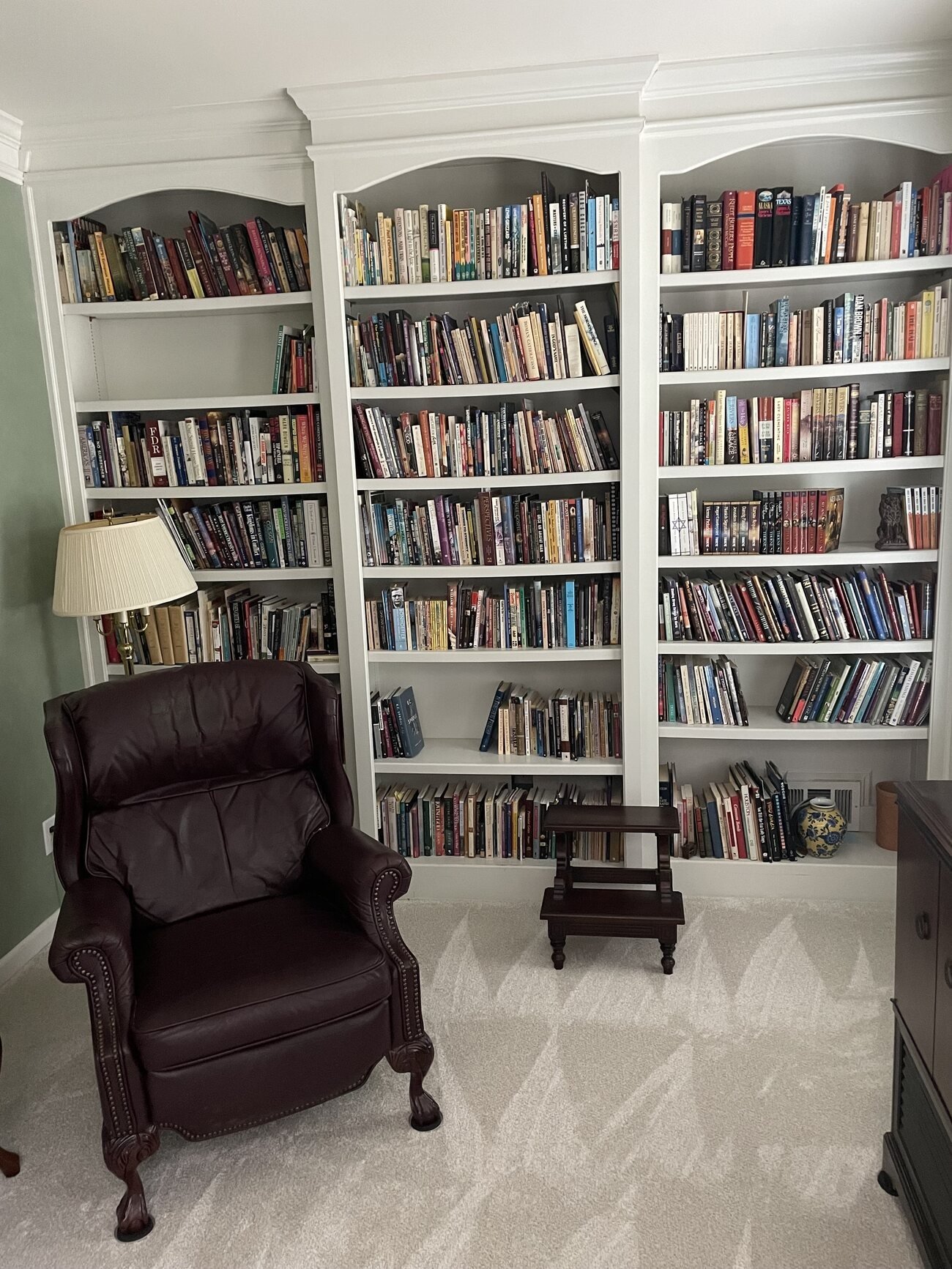 A wall of full bookshelves with a leather reading chair